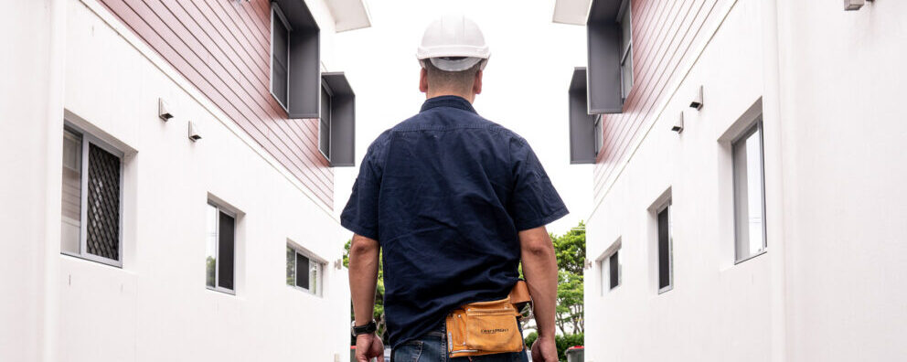 EPS Clean worker in hard hat and tool belt walking through a commercial building corridor